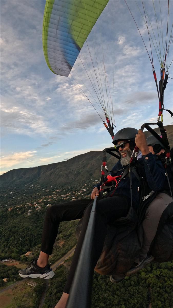 Voo duplo de parapente com passageiro sorrindo na Serra da Moeda